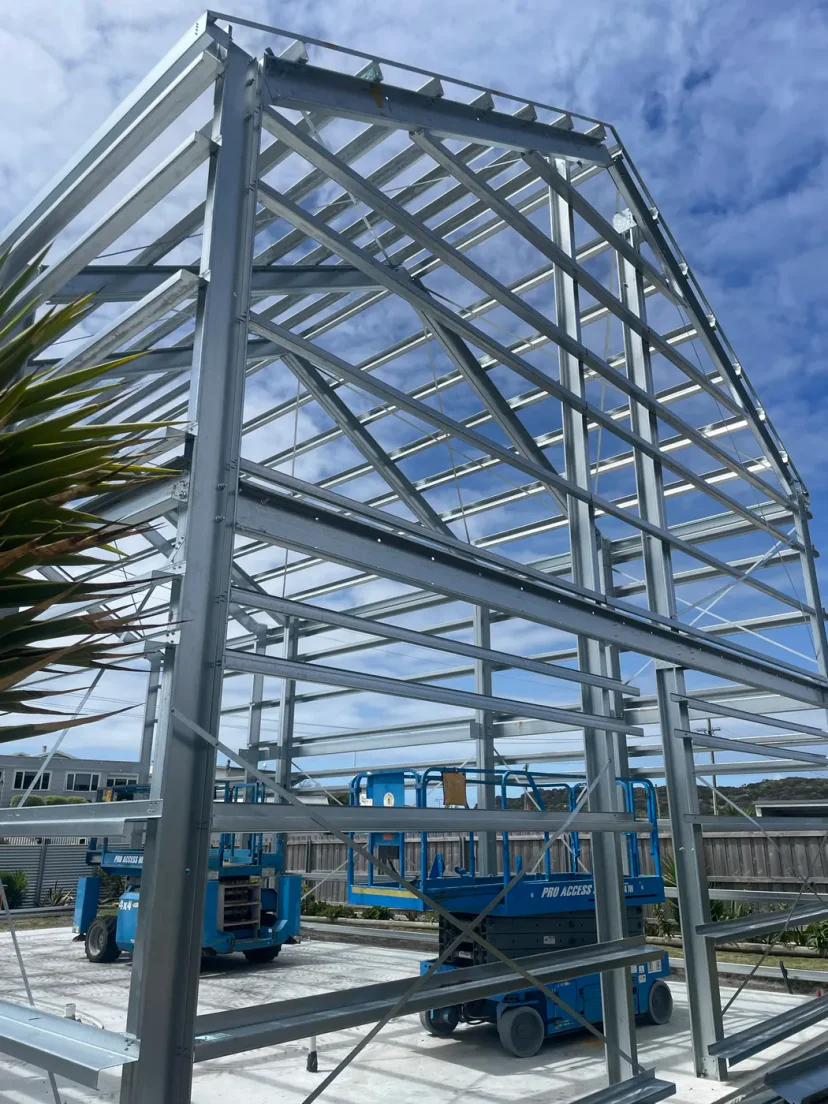 The complete galvanised portal frame skeleton of Shed Home 03 against a blue sky